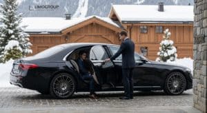 New black Mercedes S-Class 2025 by Limogroup at a snow-dusted Les Deux Alpes chalet, as a chauffeur assists a client after their premium Geneva to Les Deux Alpes transfer.